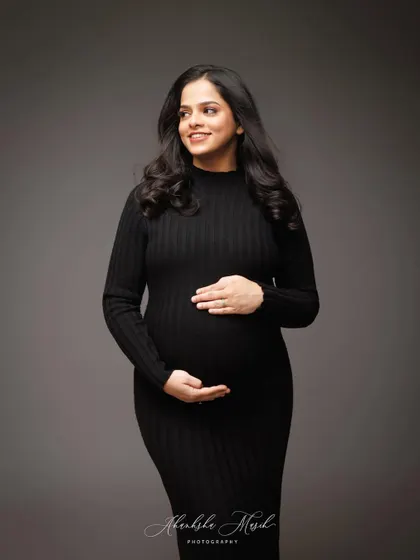 A classic and elegant portrait in a simple black dress, capturing a gentle, knowing smile.