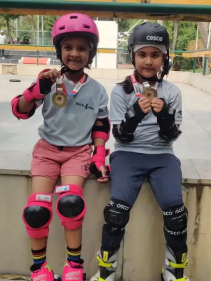 Two of our young skaters in full safety gear, proudly showing off their medals. This image perfectly captures our dual focus on safety and achievement.