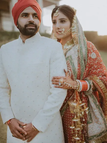 A classic portrait of a Punjabi bride and groom. The bride's hand on her groom's arm and her gentle gaze create a feeling of timeless elegance and love.
