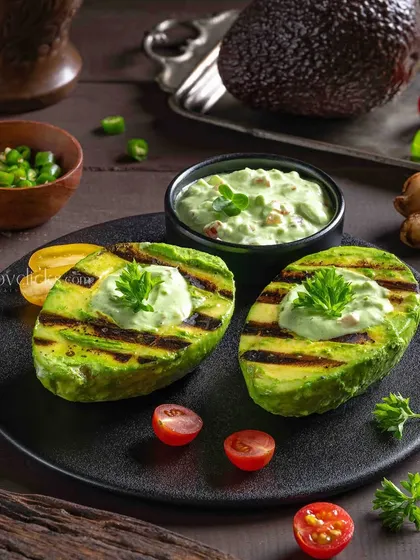 Grilled avocado halves topped with a creamy sauce, a healthy and trendy appetizer.