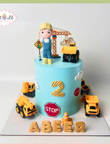 Caution: cuteness under construction! This single-tier construction cake for a 2nd birthday is surrounded by toy trucks and features a friendly fondant construction worker on top.