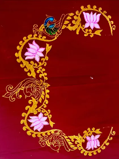 A wider view of the intricate Tanjore-style border on a deep red fabric, showcasing a beautiful pattern for a saree or wall hanging.