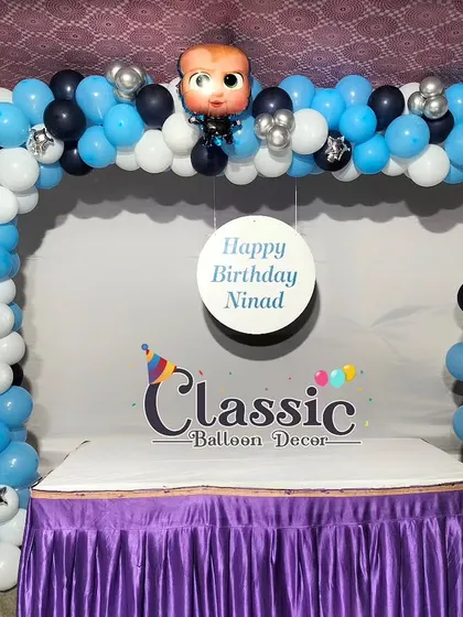 A simple yet effective Boss Baby theme for a first birthday, featuring a balloon arch over a cake table.