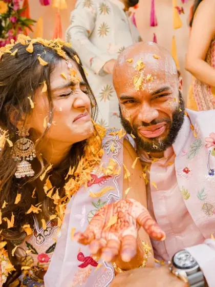 A candid moment of the couple making funny faces after being covered in flower petals. Their shared sense of humor and playful nature is evident in this shot.