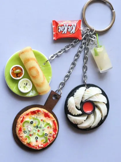 An assorted keychain featuring pizza, dosa, momos, and a KitKat, combining various food loves in one piece.