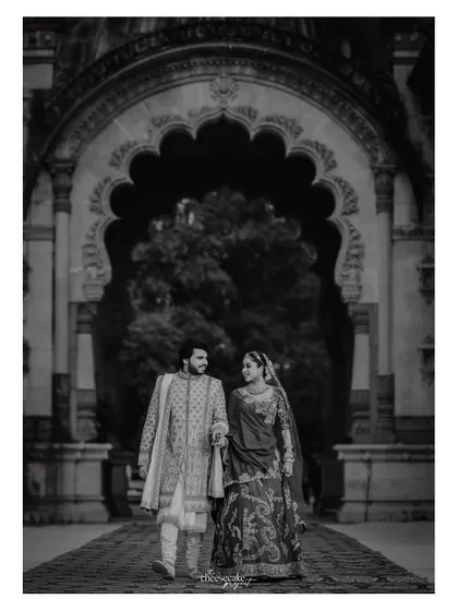 A beautiful black and white photo of the couple walking through a palace corridor.