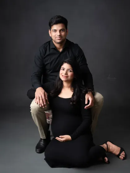 A classic seated portrait of the couple. Their coordinated black outfits and relaxed poses make for a sophisticated and modern photograph.