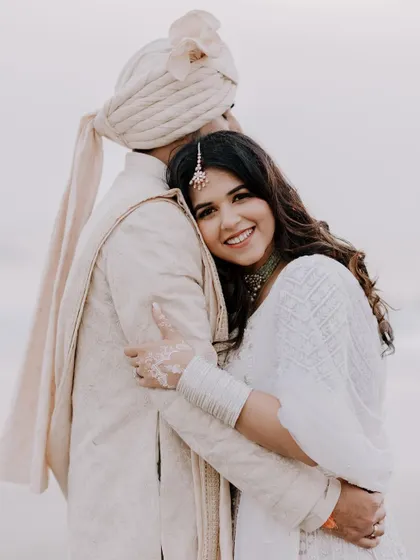 A heartfelt portrait of the bride hugging the groom from behind, her face beaming with happiness, capturing a tender moment of affection.