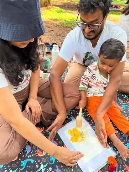 A beautiful family moment. Both parents are engaged as their child learns the technique of flower pounding, creating a shared memory through art.