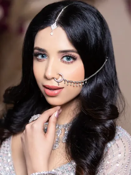 A modern reception look created by a student, featuring bright blue eyes and a sparkling silver lehenga.