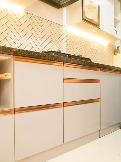 This image showcases the practical elegance of the herringbone backsplash combined with handleless cabinets and open wicker basket storage. The design is both beautiful and highly functional.