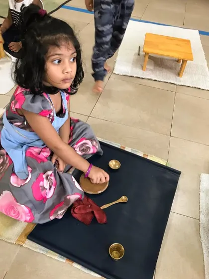 This child is engaged in the Chandan paste exercise, a beautiful practical life activity. It develops fine motor coordination and concentration while also providing a calming, sensory experience connected to our culture.
