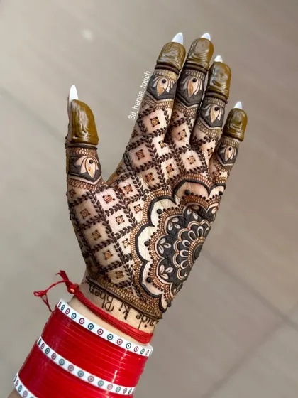 A beautiful back-hand design with a full net pattern, known as 'jaal'. The fingers are decorated with leaf motifs, and the bride's red 'chooda' bangles complete the look.