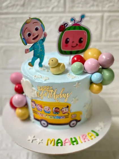 The wheels on the bus go round and round. A colourful Cocomelon-themed chocolate cake, complete with JJ, the iconic watermelon, and a school bus.
