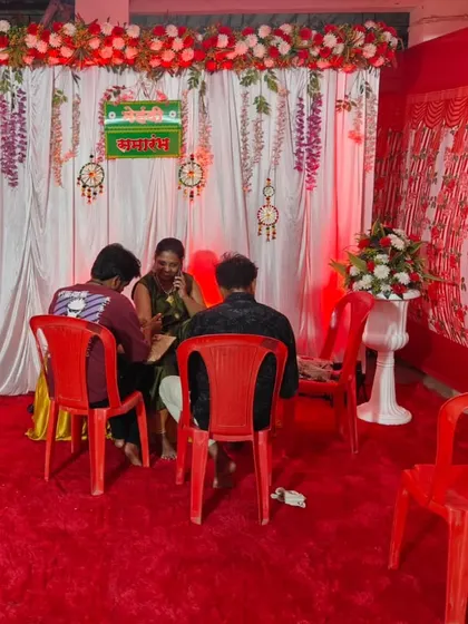 A cozy corner setup for a Mehndi ceremony. The red carpet and white backdrop with red lighting create an intimate space for the mehndi artist and the bride.
