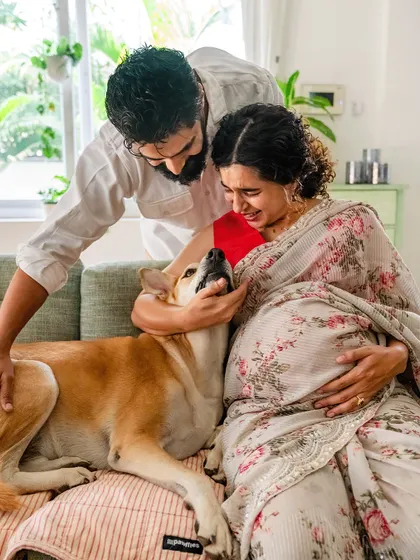 A heartwarming indoor maternity photo where a man comforts his emotional, pregnant partner while their dog looks on with love.