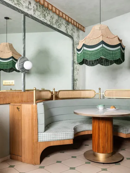 For this commercial project, we designed a space that feels nostalgic but never dated. The custom curved booth seating, upholstered in sage green and gingham, is paired with a fluted-base table and a statement scalloped pendant light, showcasing our attention to bespoke detail.