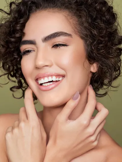 The embodiment of a successful skincare regimen. The model's radiant smile and flawless, glowing skin are the heroes of this shot, communicating health and confidence as the ultimate result of dedicated skincare.