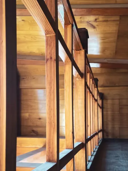 A detail of the wooden railing and beams, showcasing the craftsmanship and the play of light and shadow within the structure.