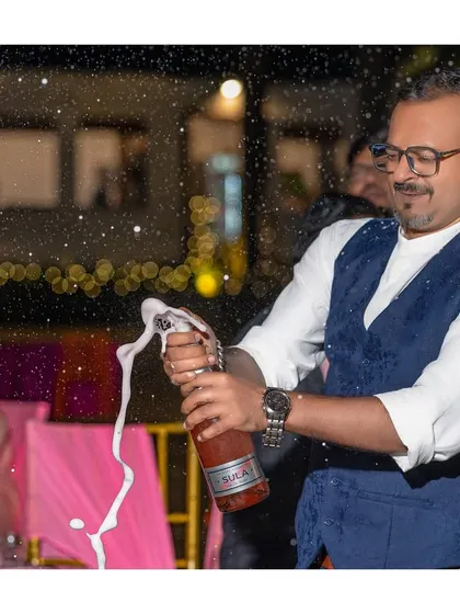 The celebration begins! A guest pops a bottle of champagne, a classic shot that signals the start of a great party.
