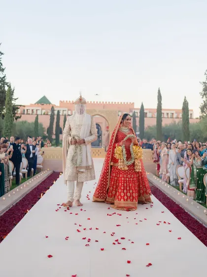 The bride and groom walking down the grand canal aisle after their wedding ceremony in Marrakech. The path, lined with guests and strewn with rose petals, made for a truly cinematic exit.