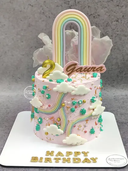 A multi-rainbow cake with a pastel rainbow topper and smaller rainbows on the side, creating a dreamy and colorful design.