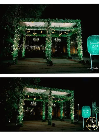 A simple yet elegant entrance arch for an evening event, covered in greenery and lit with small chandeliers.
