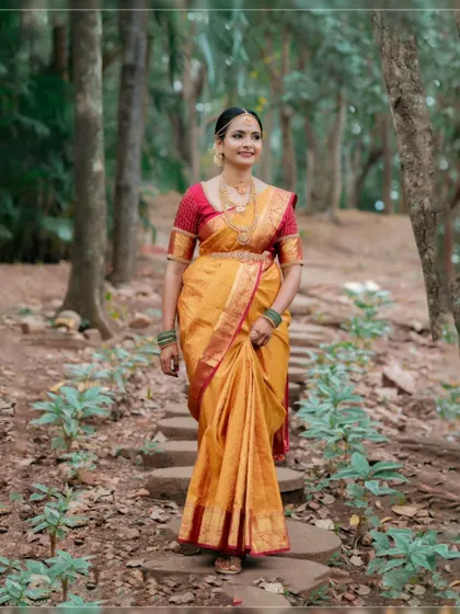 A beautiful bridal portrait of the bride walking on a stone path in a forest-like setting, her traditional saree vibrant against the natural backdrop.