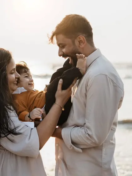 A playful family interaction by the sea. The golden hour light at the beach creates a warm and magical atmosphere for photos.