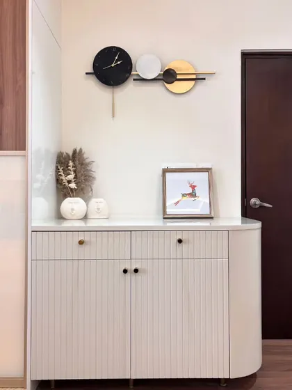 It’s the little things that make a space feel special. In this modern nook, the sleek lines of the fluted cabinet, an artistic wall clock, and subtle decor come together to reflect a shared sense of style and quiet elegance.