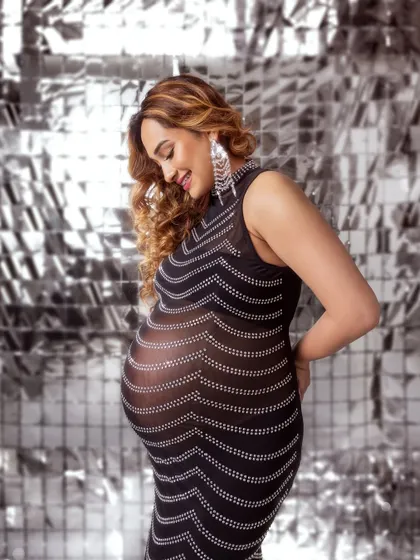 A glamorous solo shot in a sheer, sparkling dress against a silver disco backdrop. Fun, fashionable, and daring.