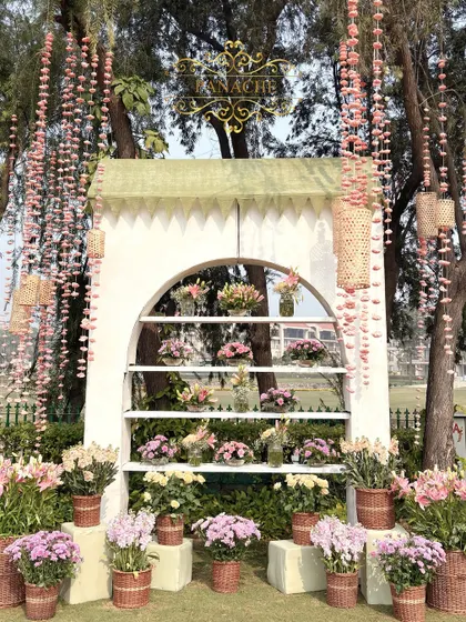 The full view of the bouquet shop photo booth, framed by trees adorned with hanging sola flowers.