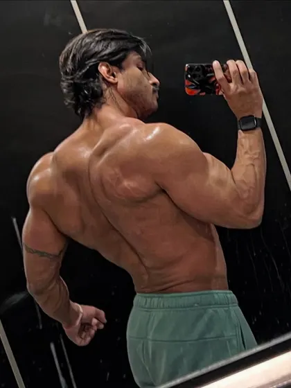 A back and bicep pose in the mirror. This shot highlights the results of a program that balances heavy lifting with aesthetic goals.