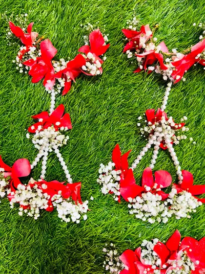 A closer look at the hath phool from the red floral baby shower set. The design uses red petals and baby's breath for a festive feel.