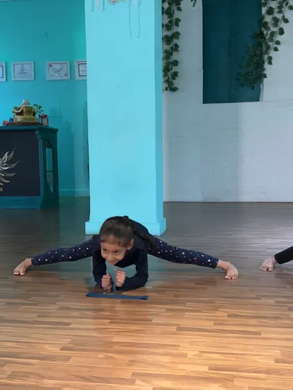A young dancer proudly holding her center split, a testament to her hard work and dedication.