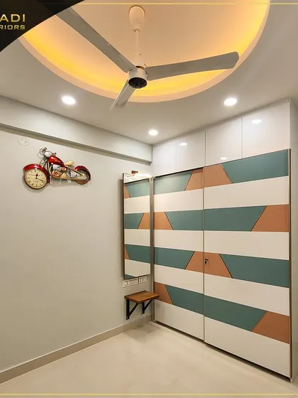 A playful and modern sliding wardrobe with a geometric pattern in white, teal, and terracotta colors. A small attached mirror and shelf add to its functionality.