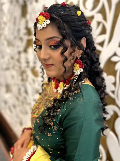 A side profile of the Haldi look, showing the intricate hairstyle and the way the floral jewelry is woven into it.