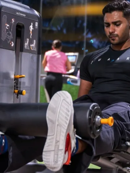 Focus is key to reaching the top. A member demonstrates intense concentration while performing a leg curl on one of our premium Precor machines, essential for building balanced lower body strength.
