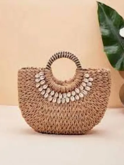 This bohemian-style handbag is woven from natural fibers and embellished with a necklace of cowrie shells. It's a perfect beach bag or holiday accessory, available for bulk orders.
