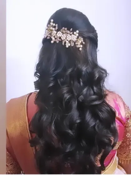 A half-up style with a twist detail and bouncy curls, finished with a beautiful pearl and gold accessory.