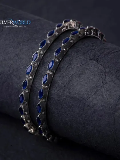 A darker, moodier shot of the blue enamel silver bangles, highlighting their deep color and sleek design.