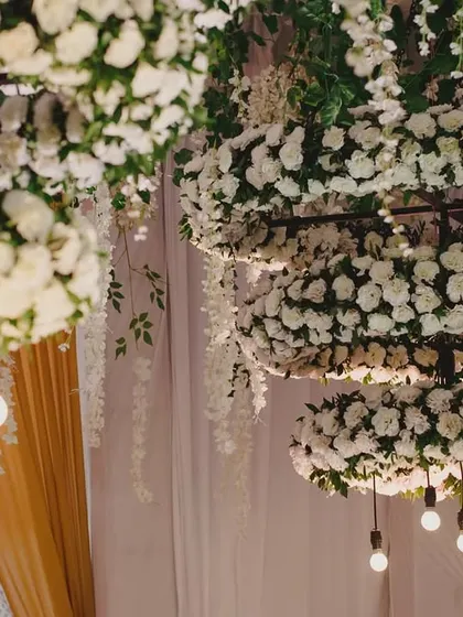 A detailed shot of the custom-made floral chandeliers, with rings of white carnations and exposed Edison bulbs for a touch of modern elegance.