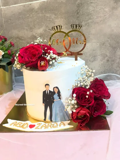 Celebrating Mr. and Mrs. with this lovely engagement cake. It features an edible print of the couple, fresh red roses, and a double ring topper.