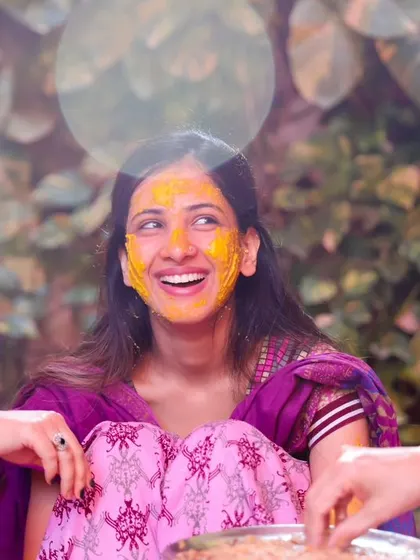 A beautiful, candid photo of the bride laughing with her friends during the Haldi. The light flare adds a dreamy, artistic touch to this joyful moment.