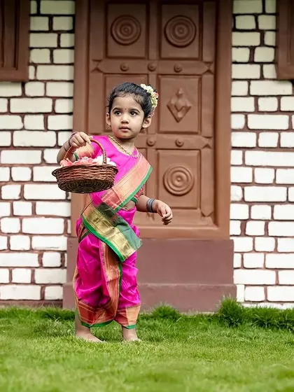 A little girl in a traditional pink saree, holding a basket of flowers. Our garden is a beautiful setting for cultural photoshoots.
