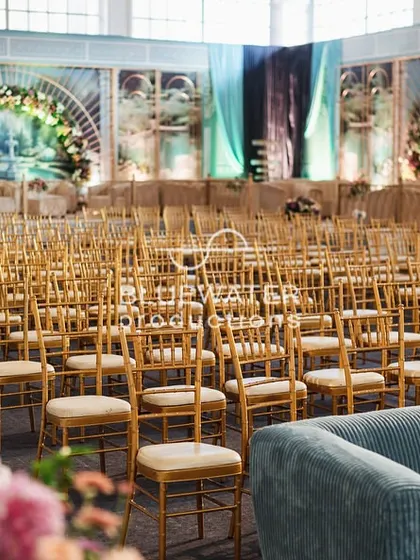 The guest seating area for the 'Blue Palace' reception, with rows of gold chairs facing a stage flanked by artistic, printed panels.
