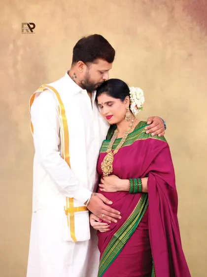 A tender moment between the parents-to-be. The dad-to-be kisses his partner's forehead as they both cradle the baby bump, a beautiful expression of their shared love.