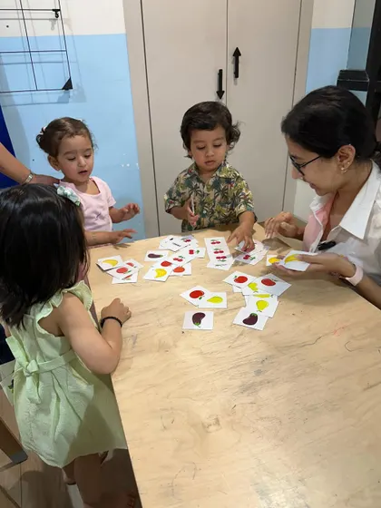 A group of children works together on a color-matching game with their trainer. Collaborative activities like this help develop social skills, turn-taking, and teamwork.