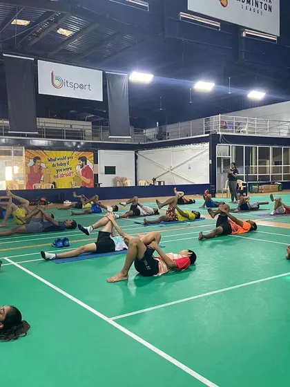 Players perform supine stretches during a yoga session. This particular exercise helps in releasing tension in the lower back and hamstrings, areas that are heavily used in badminton.