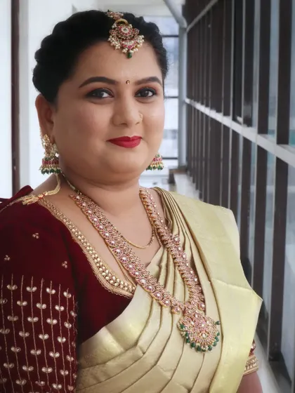 A beautiful traditional look for Ashritha. Her makeup features a classic red lip and defined eyes, paired with a stunning gold silk saree and antique jewelry.